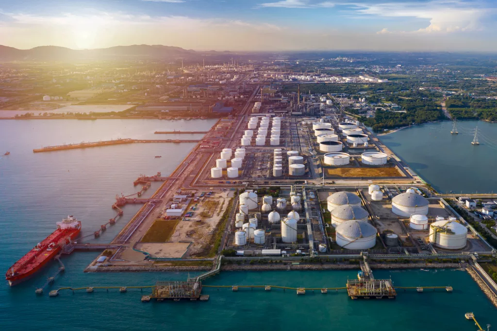An energy storage terminal on the water at sunset, with a tanker docked at the pier